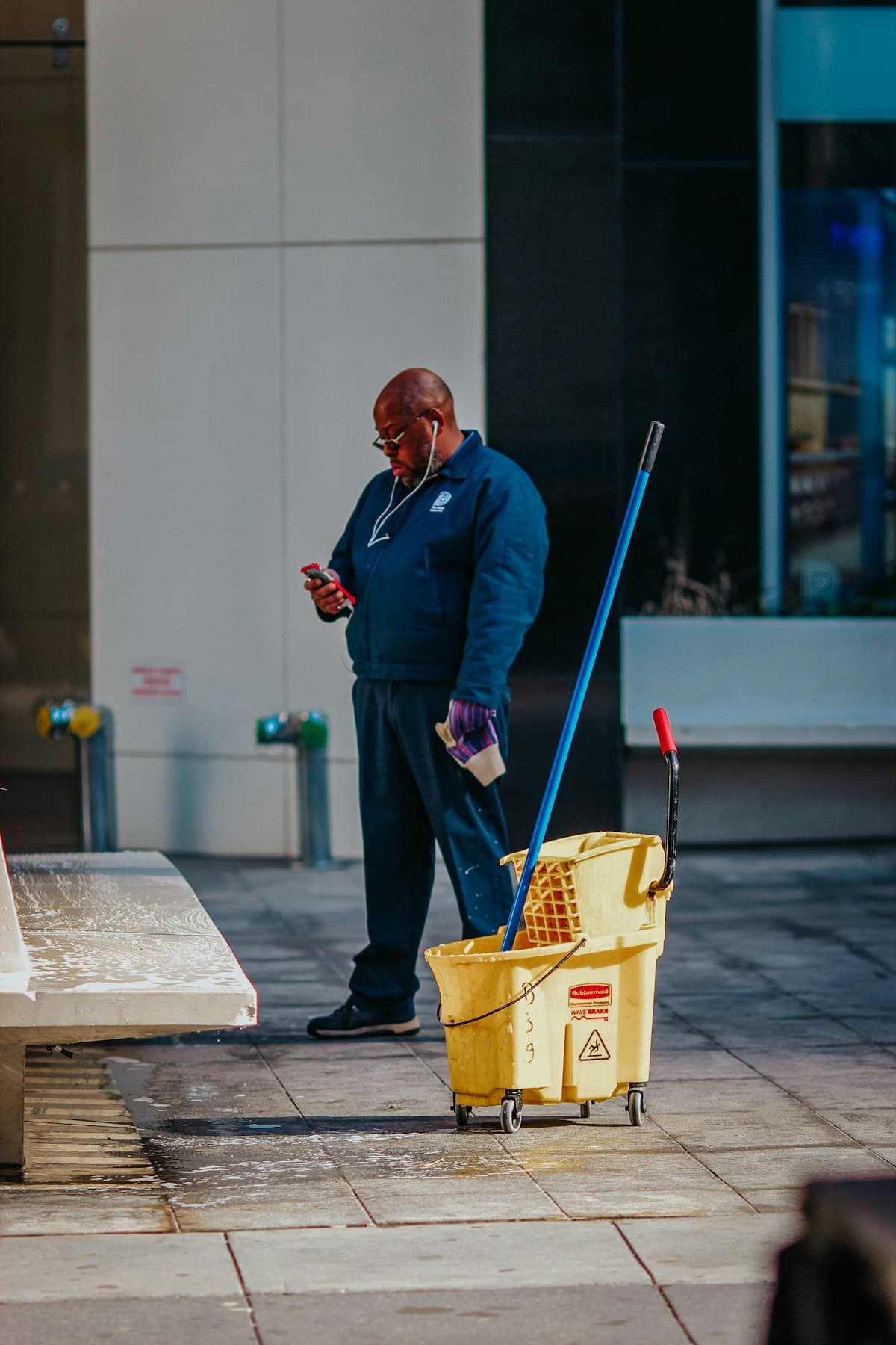 A cleaner carrying a caddy of cleaning supplies through a corridor